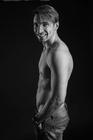 black and white studio shoot of strong athletic man on dark background. sexy bodyの写真素材