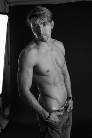 black and white studio shoot of strong athletic man on dark background. sexy bodyの写真素材
