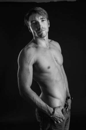 black and white studio shoot of strong athletic man on dark background. sexy bodyの写真素材