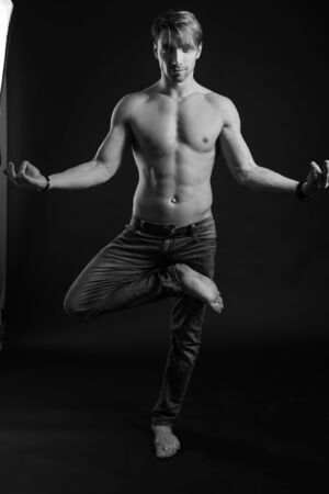 black and white studio shoot of strong athletic man on dark background. sexy bodyの写真素材