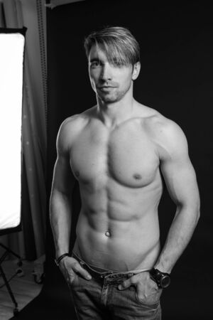 black and white studio shoot of strong athletic man on dark background. sexy bodyの写真素材
