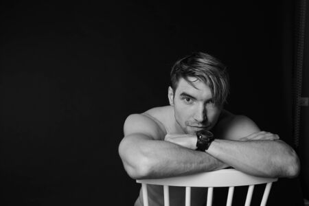 Muscular and fit young bodybuilder fitness male model posing on chair. Black and white photo. sexy body, smile and chorismの写真素材