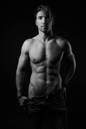 black and white studio shoot of strong athletic man on dark background. sexy bodyの写真素材