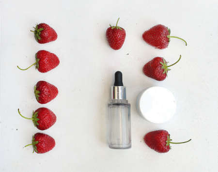 Transparent cosmetic serum in bottle with pipette next to red fresh strawberry. copy spaceの写真素材