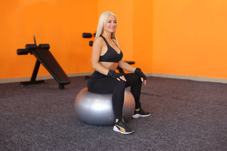 Beautiful instructor woman doing stretching fitness exercise with ball. Young woman doing exercises with gym ball. Healthy lifestyle. Sports motivation, sport conception.の写真素材