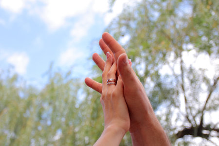 newlyweds hold hands with boats to each other against the background of the sky and trees. the...