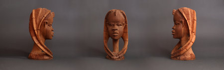 three Wooden brown statue of a womans head with pigtails. isolated on gray backgroundの写真素材