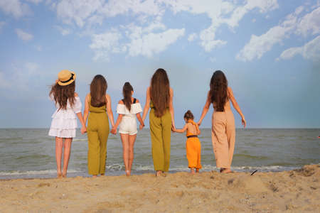 group of people embrace looking at sea. Backlight shot. Happiness, success, friendship and community concepts.の写真素材