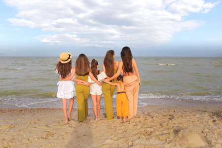 group of people embrace looking at sea. Backlight shot. Happiness, success, friendship and community concepts.の写真素材