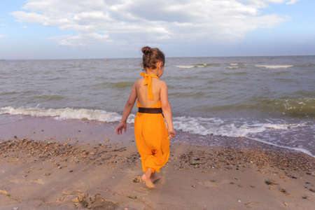 Little girl running beach shore splashing water in blue seaの写真素材