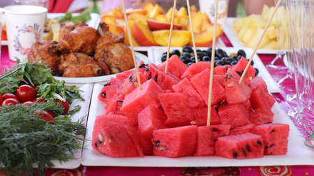 Ripe juicy red watermelon cubes on a white plate on table. Watermelon cubes ready for eatの写真素材