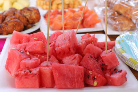 Ripe juicy red watermelon cubes on a white plate on table. Watermelon cubes ready for eatの写真素材