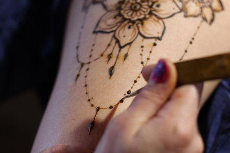 Image detail of henna being applied to hand. a lot of jewelry on the arms, bare belly. partial focus, art blur.の写真素材