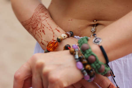 Image detail of henna being applied to hand. a lot of jewelry on the arms, bare belly. partial focus, art blur.の写真素材