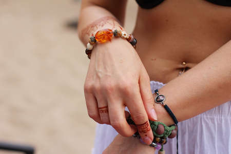 Image detail of henna being applied to hand. a lot of jewelry on the arms, bare belly. partial focus, art blur.の写真素材
