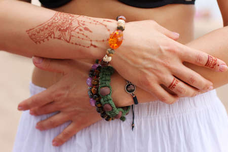 Image detail of henna being applied to hand. a lot of jewelry on the arms, bare belly. partial focus, art blur.の写真素材