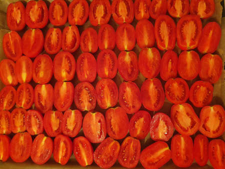 Tomato halves lie on a baking sheet in the background. The process of making sun-dried tomatoes (selective focus)の写真素材