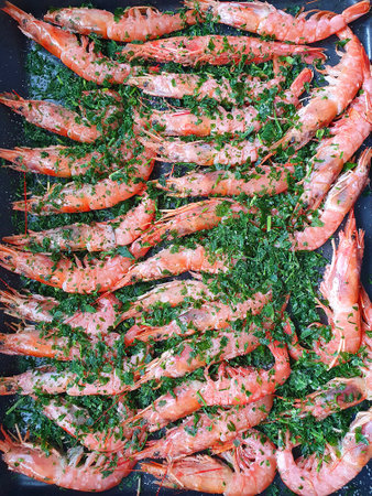 Roasted prawns shrimps with herbs on a grill skillet. Black background. top view.の写真素材