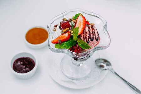 three balls of ice cream with syrup and fruit on a white backgroundの写真素材