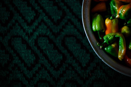 Peppers in a metal cup on a carpet background with space for text