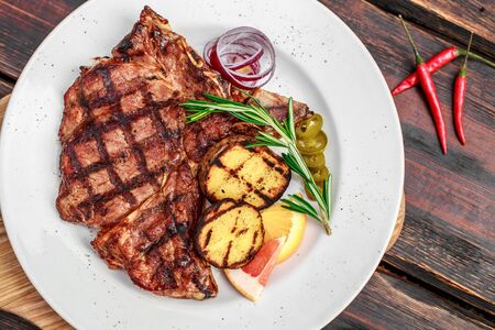 A large steak with spices and vegetables on the grillの写真素材