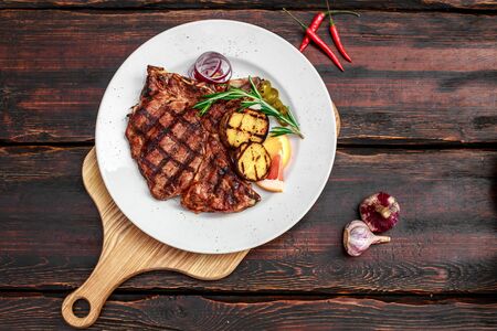 A large steak with spices and vegetables on the grillの写真素材