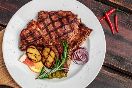 A large steak with spices and vegetables on the grillの写真素材