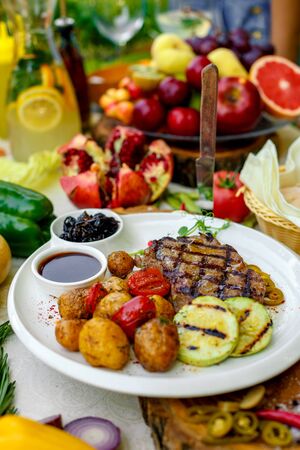 BBQ, juicy steak with grilled vegetables and sauce on a white plateの写真素材