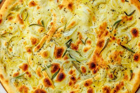 hot pizza with onions and basil on a wooden surface with vegetables on a white tableの写真素材