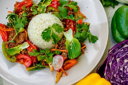 Thai meat with vegetables on a decorated table in a white plateの写真素材