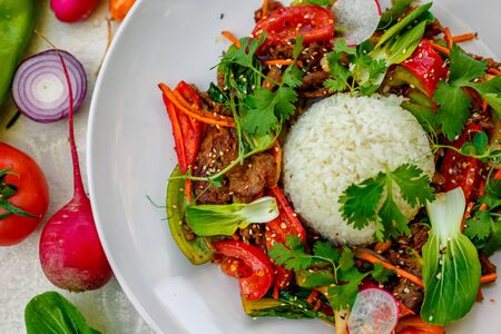 Thai meat with vegetables on a decorated table in a white plateの写真素材