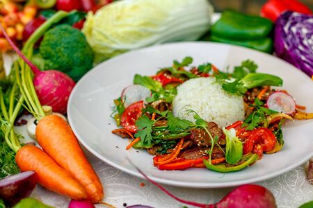 Thai meat with vegetables on a decorated table in a white plateの写真素材