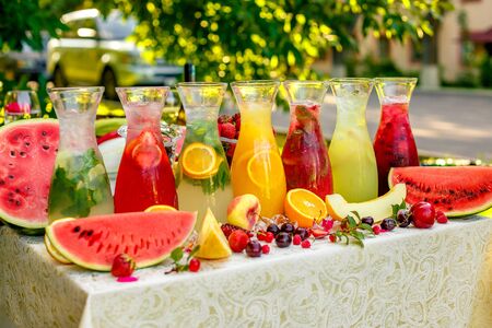 fresh lemonade collection (watermelon, orange, lemon, strawberry and berry) in the street, on a wooden table with fruitの写真素材
