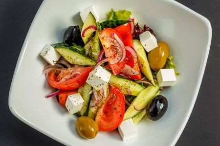fresh greek salad with tomatoes, feta cheese, onions, olives and cucumbers, healthy food, isolatedの写真素材