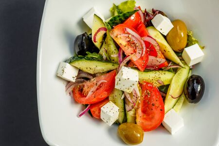 fresh greek salad with tomatoes, feta cheese, onions, olives and cucumbers, healthy food, isolatedの写真素材