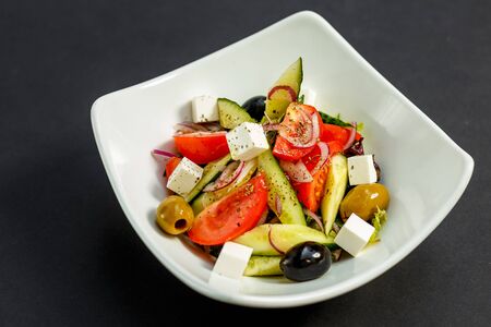 fresh greek salad with tomatoes, feta cheese, onions, olives and cucumbers, healthy food, isolatedの写真素材