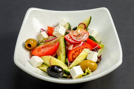 fresh greek salad with tomatoes, feta cheese, onions, olives and cucumbers, healthy food, isolatedの写真素材
