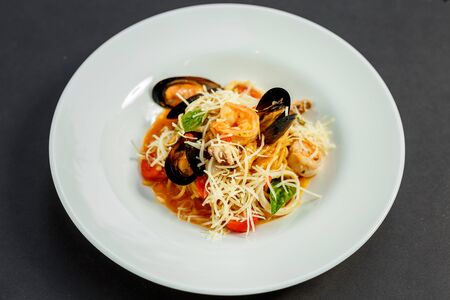 delicious Italian pasta with cheese and seafood (mussels, shrimps) on a white plate, isolatedの写真素材