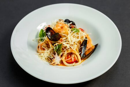 delicious Italian pasta with cheese and seafood (mussels, shrimps) on a white plate, isolatedの写真素材
