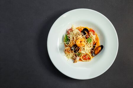 delicious Italian pasta with cheese and seafood (mussels, shrimps) on a white plate, isolatedの写真素材