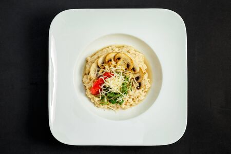 rice porridge with mushrooms, parmesan cheese, arugula and tomatoesの写真素材