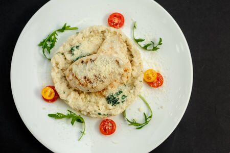 appetizing chicken breast with cheese, tomatoes and arugula with rice garnishの写真素材