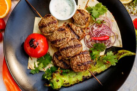 kebab with pita bread and grilled vegetables on a decorated tableの写真素材