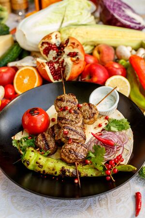 kebab with pita bread and grilled vegetables on a decorated tableの写真素材