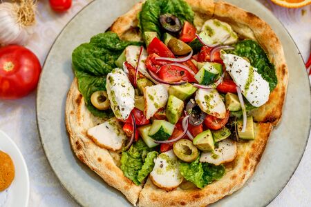 salad with chicken cheese and vegetables on a flat cake on a decorated tableの写真素材