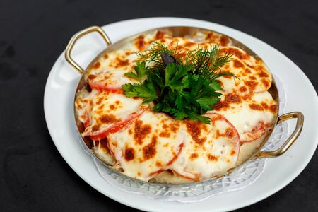 casserole with meat cheese, tomato and potatoes with greensの写真素材