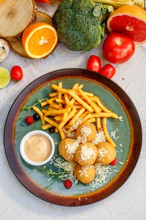 Crispy potato balls with soft melted cheese and french fries on decorated tableの写真素材