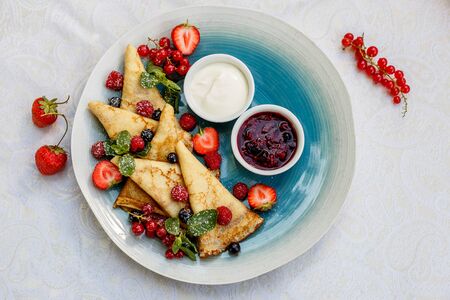 pancakes with fresh berries, jam and sauce on the decorated tableの写真素材