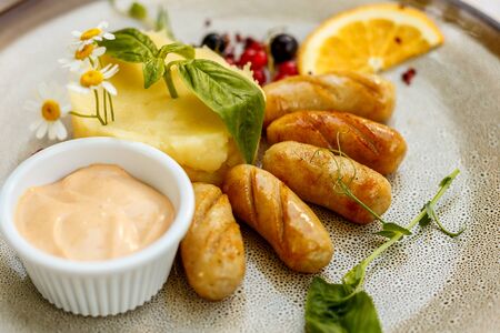 chicken sausages with mashed potatoes and sauce on a painted tableの写真素材