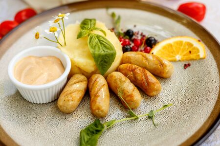 chicken sausages with mashed potatoes and sauce on a painted tableの写真素材